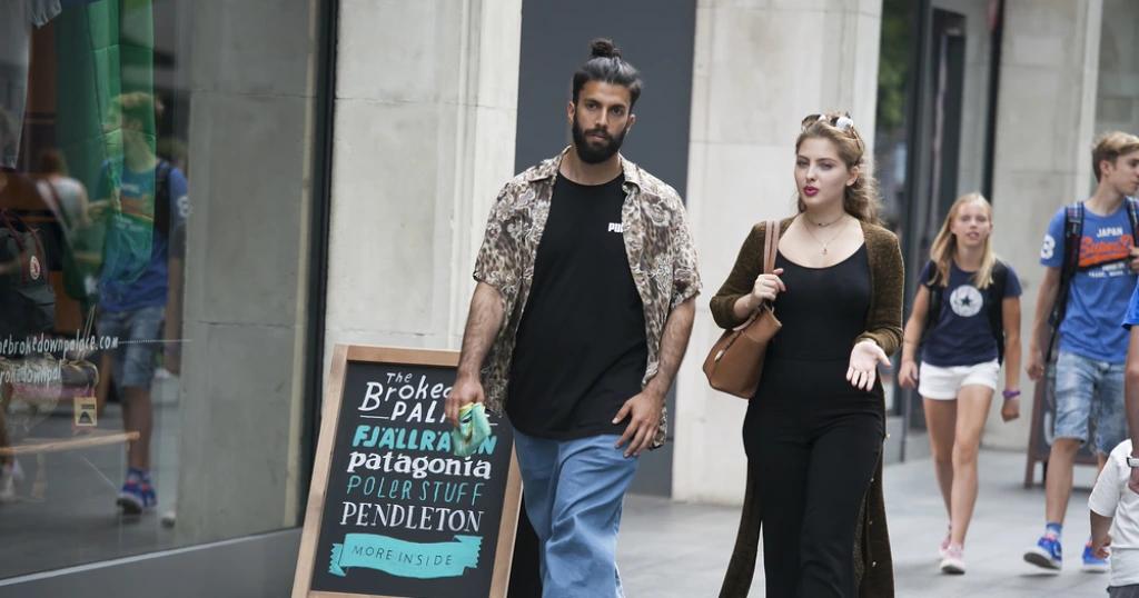 People walking on a UK street, showcasing diverse urban fashion styles. Relevant to the topic 'UK Visa From Pakistan