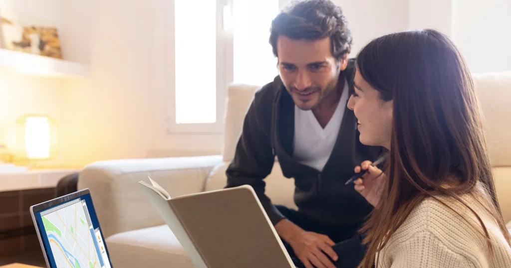 Two business professionals reviewing a computer screen and documents together, discussing local business strategy. Local SEO for Multiple Locations.