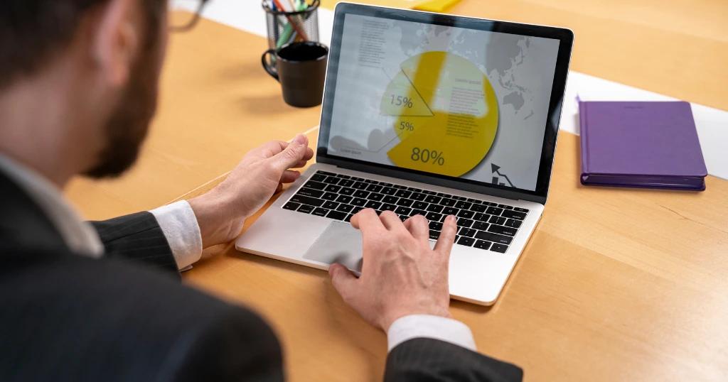 A businessman analyzing Local Service Ads in London on a laptop, displaying a pie chart with marketing data.