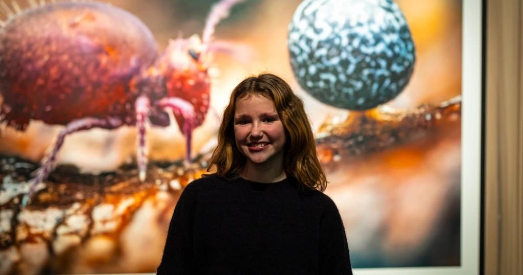 Young woman smiling in front of a vibrant, close-up nature exhibit. Relevant to the topic 'UK Visa From Pakistan