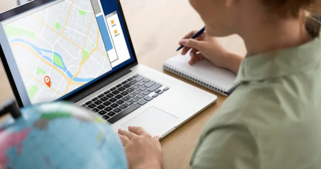 A person using a laptop to analyze a digital map on the screen, taking notes. Local SEO for Multiple Locations.
