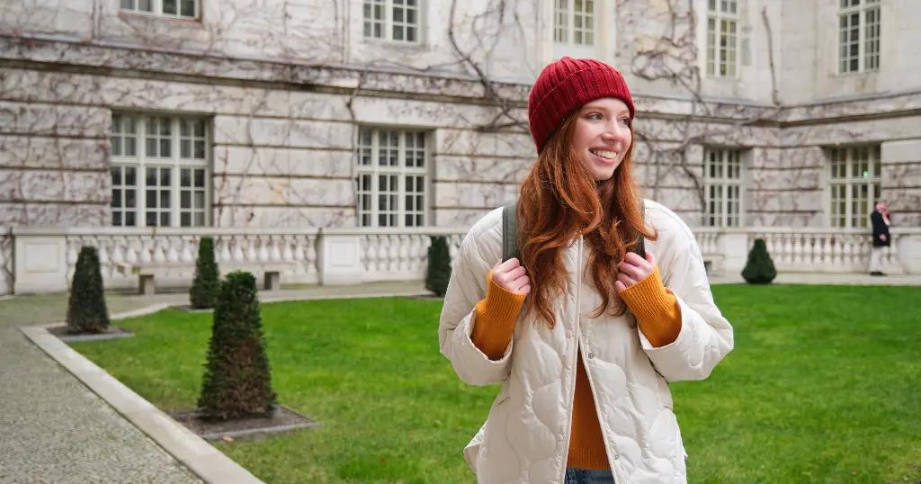 A smiling woman in a stylish winter outfit at a historical site – Get expert UK Visa Consultants in Lahore for your travel plans.