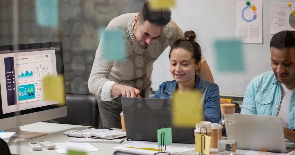 Team collaborating on AI-powered digital marketing analytics and strategies, with charts and graphs displayed on a laptop.