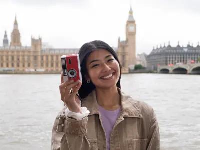 A happy traveler holding a camera near Big Ben, London – UK Visa Consultants in Lahore can help you explore the UK easily.