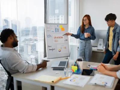 Group discussing AI-powered digital marketing plans with charts on a whiteboard during a team meeting in a corporate office.