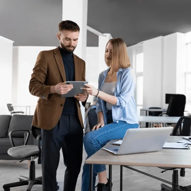 A professional marketing consultancy team in the UK discussing strategies for business growth, with charts and graphs displayed on a screen.