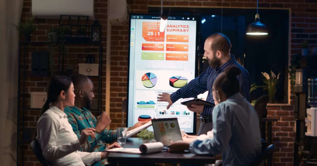 Group of digital marketing specialists analyzing social media metrics and discussing campaign strategies in a Birmingham office.