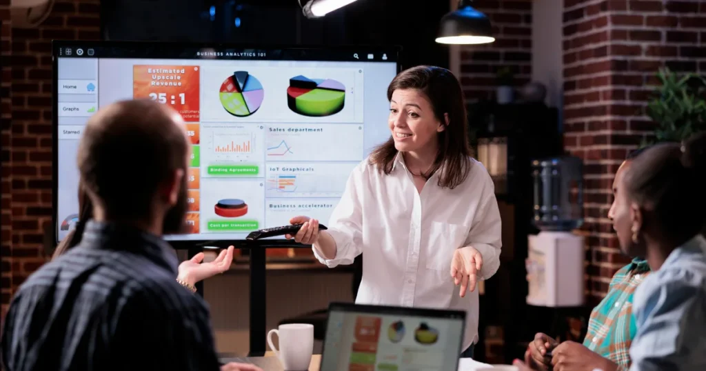 Team of digital media marketing professionals collaborating in a modern office in Birmingham, discussing strategies and analyzing data on laptops and tablets.